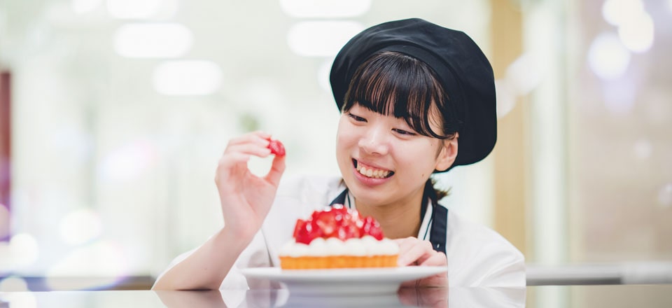 ケーキのデコレーションを行う学生